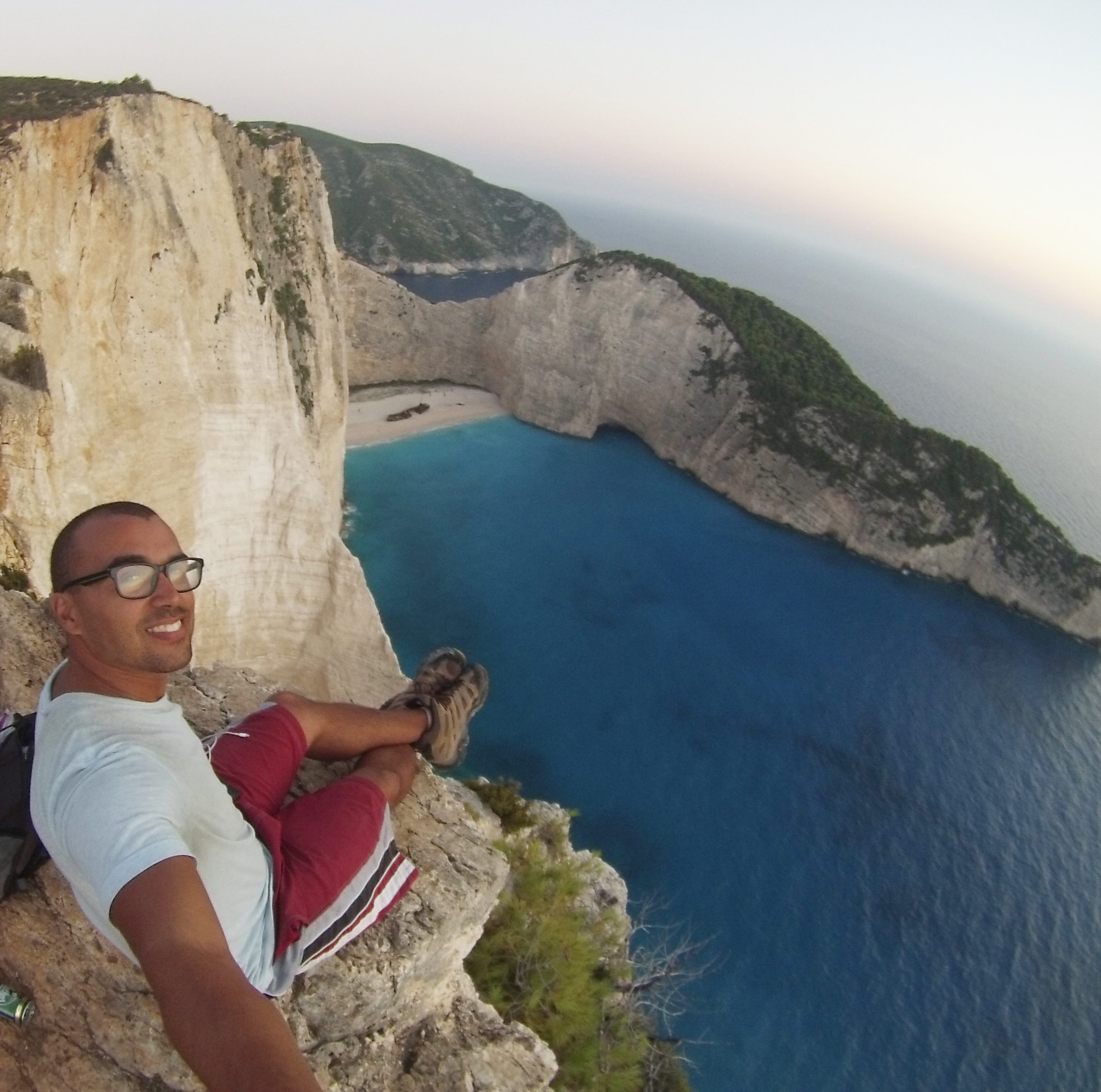 A joyful image of the user standing on the stunning Navagio Beach in Zakynthos, Greece. Photo above the turquoise waters and the iconic shipwreck nestled in a sandy cove surrounded by towering cliffs in this picturesque Greek paradise.