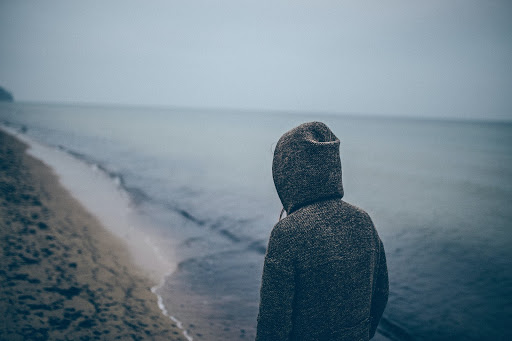 person with hoodie looking at beach