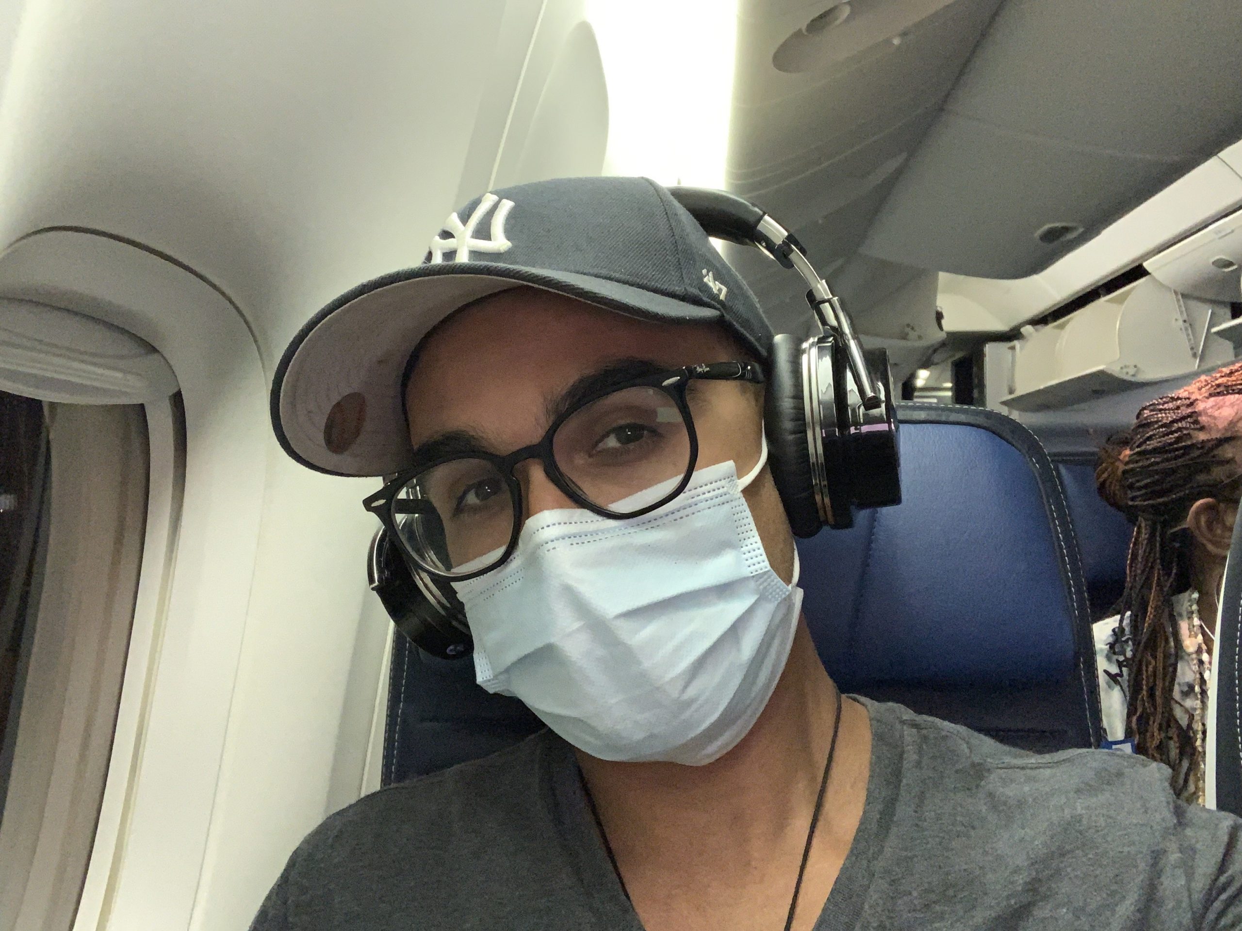 covid travel plane with headphones and facemask
