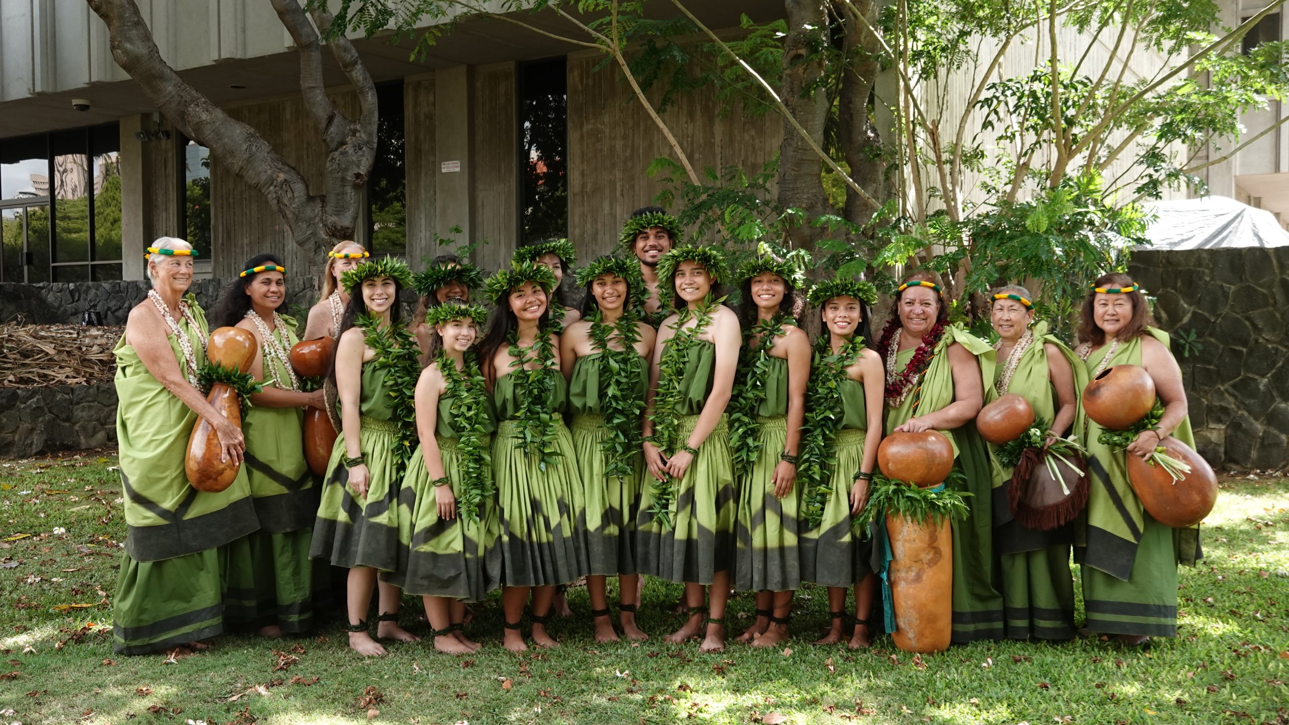 hula hālau posing for photo with ipu heke and traditional attire for dance